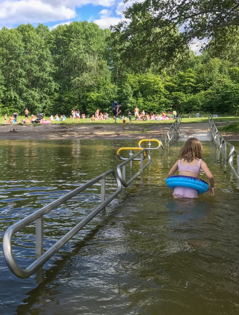 Tjej som går upp från badet via en rullstolsramp.